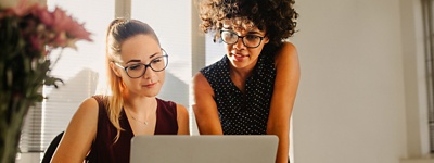 Two women with glasses look at a computer screen