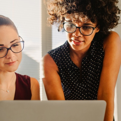 Two women with glasses look at a computer screen