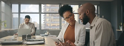Office workers in a conference room discussing information on a tablet
