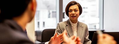 An executive at a boardroom table, listening to her colleague speak.