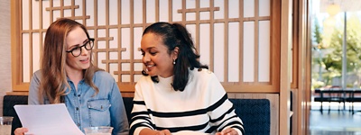 Two women smiling while looking at files