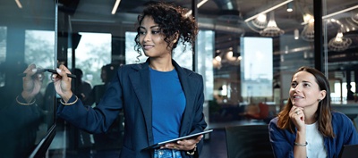 Two colleagues using a digital whiteboard in an office.