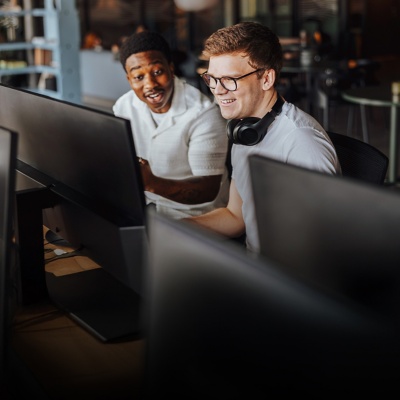 Two men looking at a computer screen in a startup office smiling