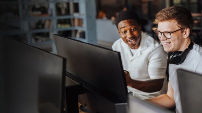 Two men looking at a computer screen in a startup office smiling