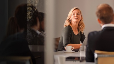Several people sit around an office table during a board meeting