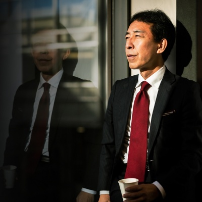 A finance businessman standing outside of an office holding a coffee cup.