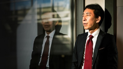 A finance businessman standing outside of an office holding a coffee cup.