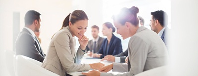 A group of professional office workers collaborating around a table in a conference room.