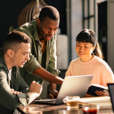 Three people collaborating with man pointing at laptop