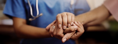 A nurse holding a patients' hand.
