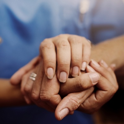 A nurse holding a patients' hand.