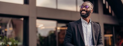 A photo of a smiling man walking outside holding a tablet.