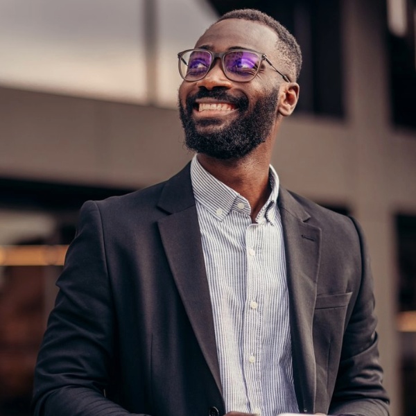 A photo of a smiling man walking outside holding a tablet.