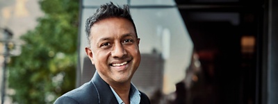 A CFO standing on his office balcony, smiling at the camera.