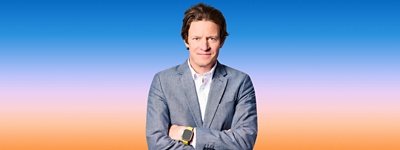 Text: Man in suit smiling at camers