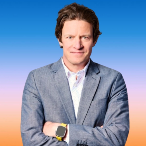 Text: Man in suit smiling at camers