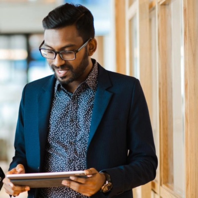 Two HR colleagues walking down an office corridor while looking at an iPad.