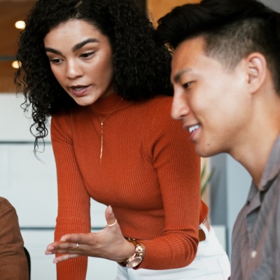 Coworkers looking at laptop woman standing and referencing screen