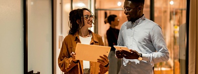 Coworkers with glasses smiling at each other while holding tablets