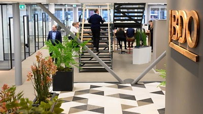 Image of a man walking up the steps  with people sitting at a table behind the steps.