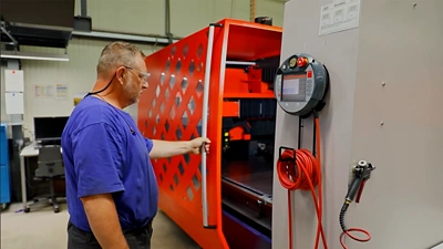 An older male employee wearing a blue shirt and safety glasses.