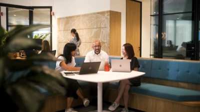 Image of three people sitting at a table with their laptops open.