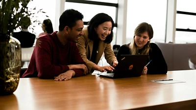 Image of three employees discussing over desk