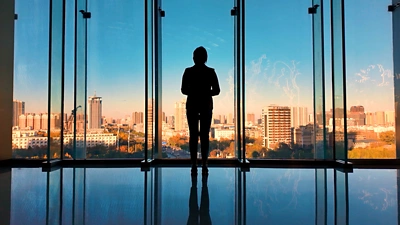 A person standing in a building looking out over a city.