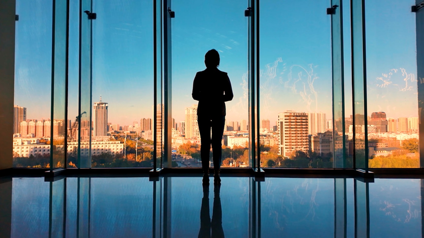 A person standing in a building looking out over a city.
