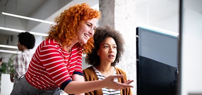 Two colleagues working at a desk looking at a computer screen.
