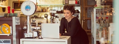 Owner of coffee shop using a laptop