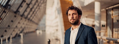 A man standing in a modern office block foyer.
