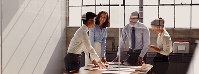 Group of colleagues standing and talking in room with windows