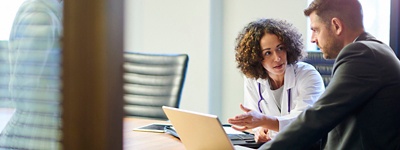 Two healthcare providers conversing in a conference room. 