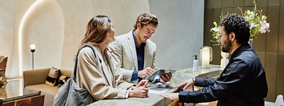 Hotel employee helping customers check-in at a lobby front desk