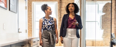 Dos mujeres hablando y caminando por una oficina