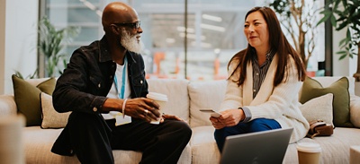 Two colleagues sitting on a sofa together in an office setting 