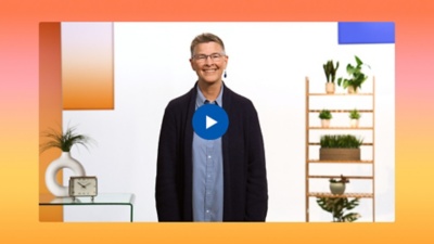 A smiling Tammy Snow stands in a bright, modern office setting with a play button overlay. They wear a blue button-down shirt and a navy cardigan, set against a vibrant orange and yellow gradient border.