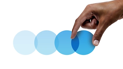 Main sélectionnant le rond bleu le plus lumineux, qui symbolise une meilleure expérience que les autres.