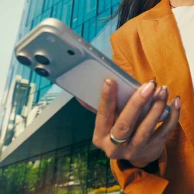 A closeup image of a female professional with mustard blazer using phone outdoors. 