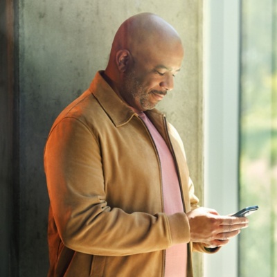 Male professional using mobile device standing by window.