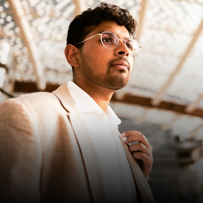 Bespectacled person in a blazer and collared shirt looking off-frame