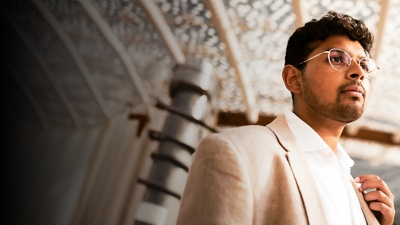 Bespectacled person in a blazer and collared shirt looking off-frame