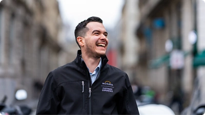 Empleado sonriente mirando al horizonte. Lleva puesta una cazadora de 鶹ý.