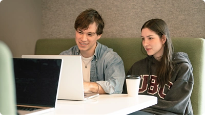 Two employees sitting together in front of a laptop.