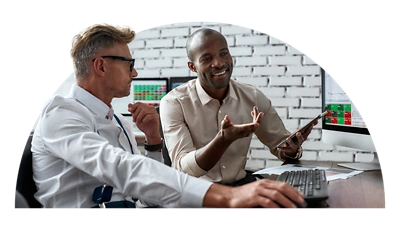 コンピュータを前にして話し合っている 2 人の従業員