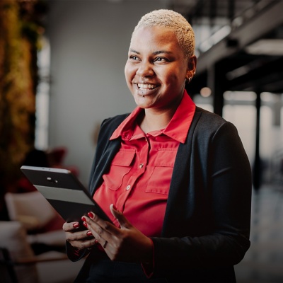 A smiling businessperson standing and holding a tablet.