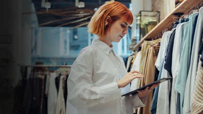 [woman in a clothing store looking at a tablet]