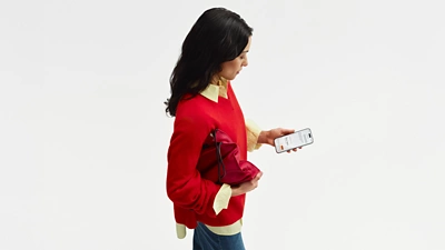 Woman with red clutch using Sana on phone.