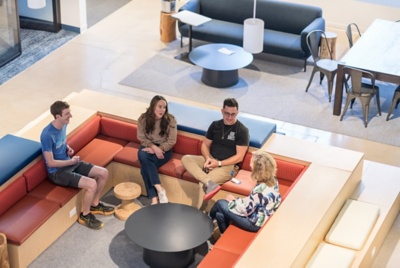 Un grupo de empleados sentado escucha a un empleado hablando de pie.